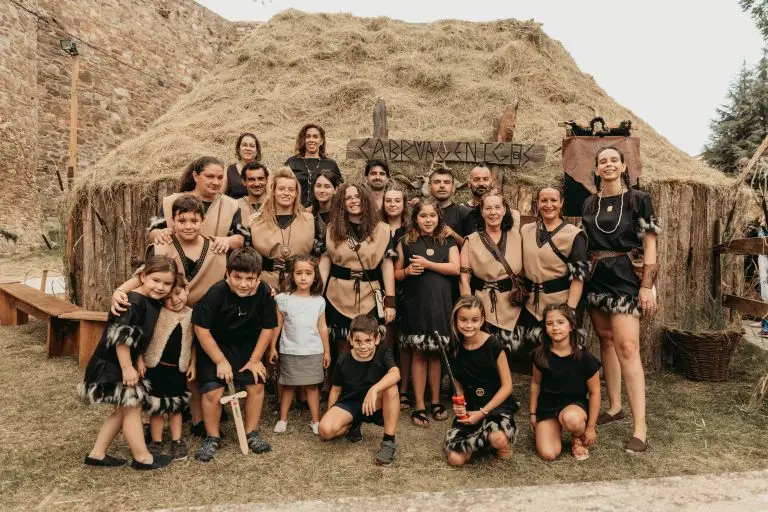 Foto grupal de la tribu astur Cabruagénicos con túnicas beige y negro con flecos de piel, frente a su palloza en el poblado astur de Astorga