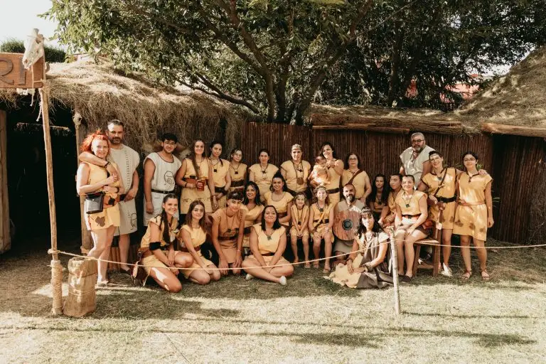 Foto grupal de la tribu astur Tiburi con túnicas amarillo ocre y caetra redonda frente a su palloza en el poblado astur de Astorga